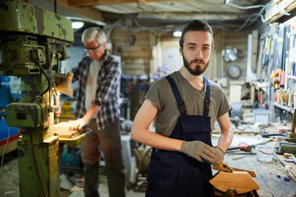 工作機械加工を施した若い木工職人が先輩社員を背景に木工加工を行う — ストック写真