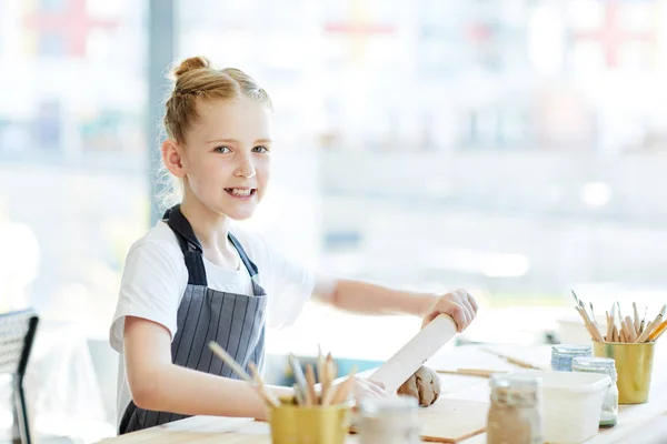 レッスンで工芸品のスタジオで職場で粘土で作業ローリングピンを持つ小さな女の子 — ストック写真