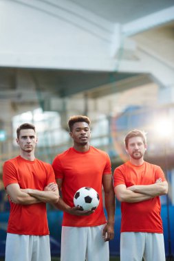Üç genç futbolcular Stadyumu kamera önünde duran beyaz şort ve kırmızı t-shirt