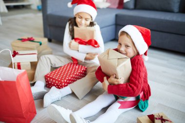 Noel Baba şapkalı iki mutlu kız noel hediyelerini kucaklayarak kutulara tıkılmış