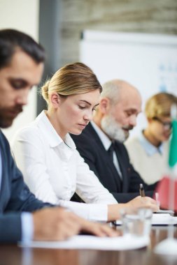 One of delegates making notes at working conference among her foreign colleagues clipart