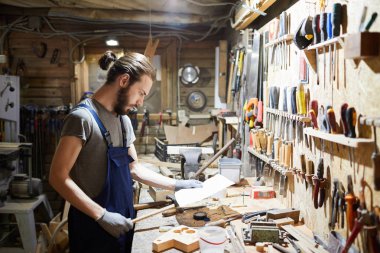 İş elbisesi ve eldiven giyen genç adam işe gitmeden önce kağıt okuyor.