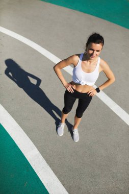 Çekici gülümseyen genç bayan Stadı'nda duran ve kalçalarına geçiş sırasında elele smartwatch tam anlamıyla uyum