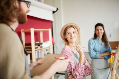 Kalem şüskül tarafından ayakta ve resim dersinde onun grup arkadaşı konuşuyor mutlu kız