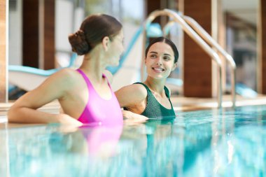 Spa merkezinde Yüzme Havuzu içinde otururken konuşmayı mayo'de iki dinlendirici kız