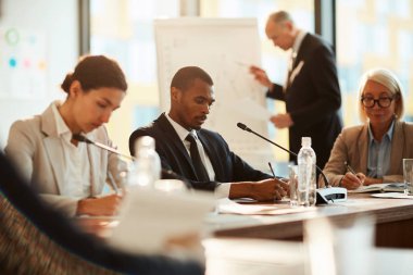 Kültürlerarası öğrenenler raporlarıyla hazırlanıyor veya oditoryumdaki kağıtlar üzerinde doğru cevapları işaretliyor