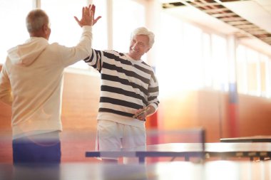 İki mutlu kıdemli tenis ya da ping pong oyuncuları başarılı oyun sonra başka bir yüksek beş veren