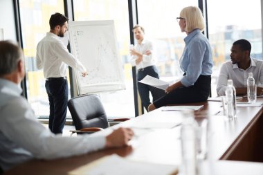 Konferans öncesi brifingde çalışma noktalarını tartışan genç ve olgun finansörler grubu