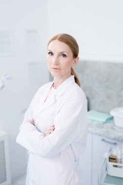 Kamera önünde dururken göğüs kollarını geçen üniformalı modern klinisyen