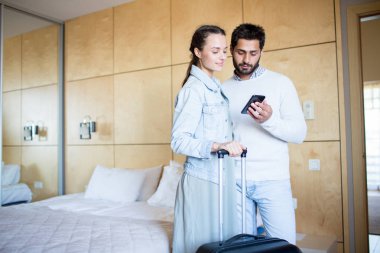 Otel odası bırakarak net en yakın uçuşlar için arayan bavul ile genç çift