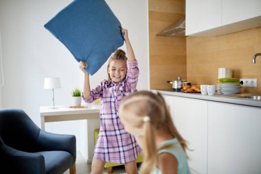 İki küçük oyuncu kız evde boş zamanlarında yastıkile mücadele ederken eğleniyor