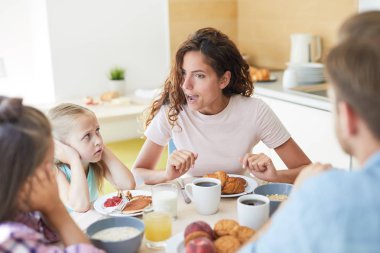 Genç bir kadın mutfakta servis masasında yaramaz küçük kızlarıyla konuşuyor.