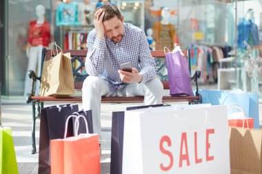 Paperbags yığını eğilerek süre alışveriş sonra dengesini kartı kontrol smartphone ile genç shopper