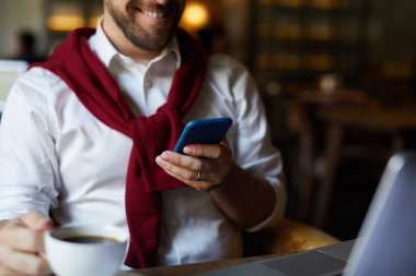 Kafede otururken akıllı telefon mesajlaşma veya iletişim arayan zarif işadamı