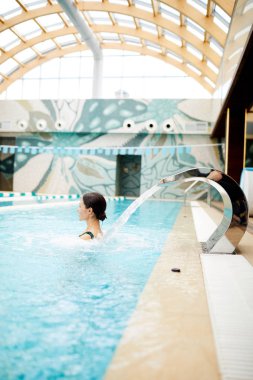 Su genç kadının sırtında duran spa yüzme havuzunda su sıçramalarına