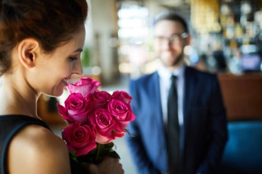 Mutlu esmer kadın erkek arkadaşı gelen romantik pembe güller demet bakıyor