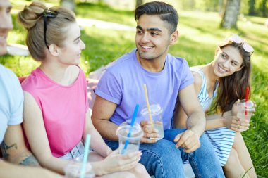 Açık havada arkadaşları arasında konuşurken içki ile yakışıklı adam kız arkadaşı bakarak