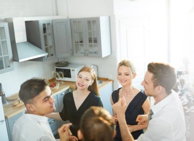 Genç arkadaşlar mutfakta daireler çiziyor, dans ediyor ve ev partisinin tadını çıkarıyorlar.