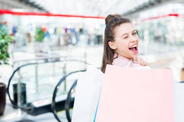 Mutlu ve flört müşteri arıyor ve sen, alışveriş merkezinde göz kırpıyor paperbags ile