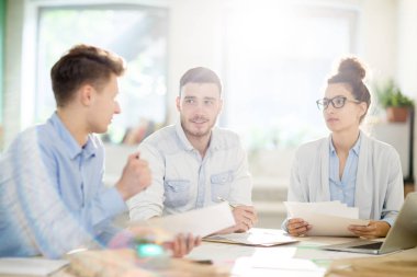 Üç genç profesyonelin masaya oturarak ve bilgi tartışması ile toplantı