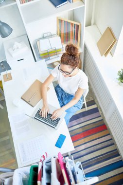 Genç yaratıcı iş kadını dizüstü bilgisayarın önünde oturuyor ve internette yeni fikirler arıyor.