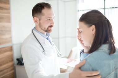 Young clinician comforting upset patient after telling her diagnosis