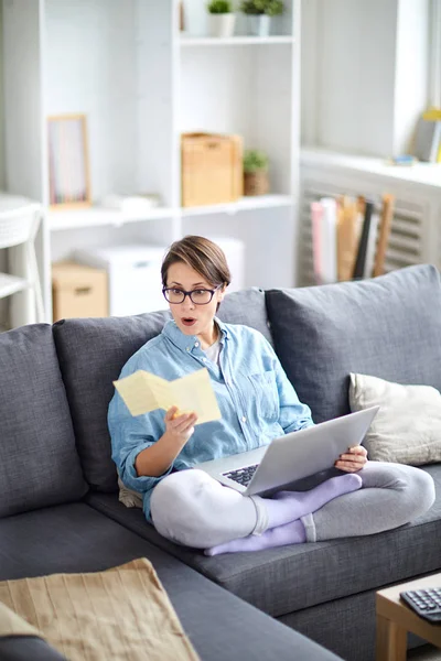 Förvånad Ung Kvinna Sitter Soffan Och Titta Resebroschyr Medan Väljer — Stockfoto