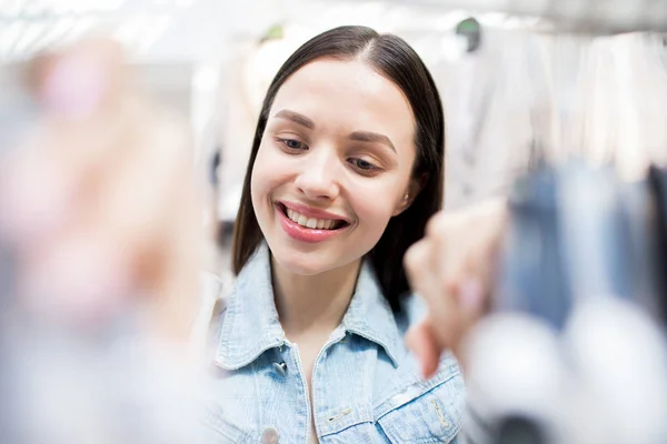 在大型商场的一个部门里 微笑的女人在衣架上翻看时髦的衣服 — 图库照片
