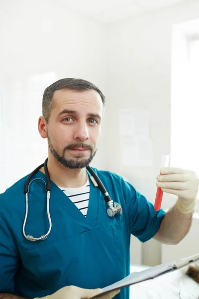 血液検査で医療文書とフラスコを保持するユニフォームで手袋をした獣医 — ストック写真