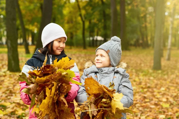 Dos Escolares Interculturales Con Montones Hojas Amarillas Mirándose Parque Otoño —  Fotos de Stock