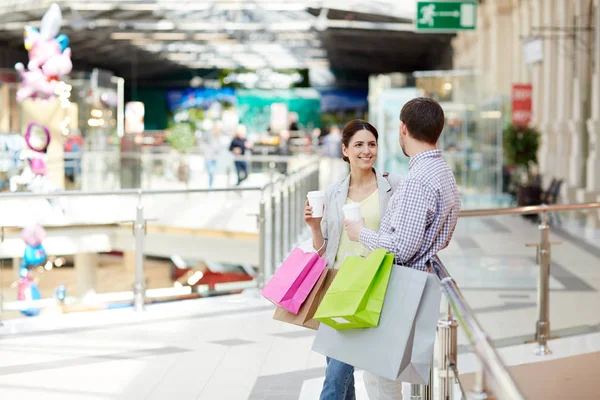 Young Couple Drinks Paperbags Leaning Railings Modern Mall Having Talk — Stock Photo, Image