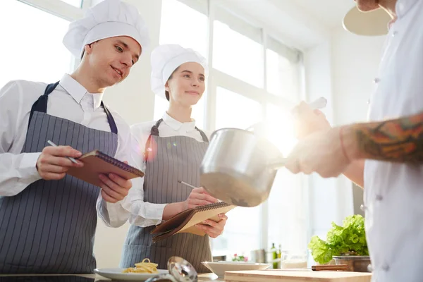 Estudantes Curiosos Positivos Chapéus Chefs Avental Fazendo Anotações Enquanto Obtêm — Fotografia de Stock
