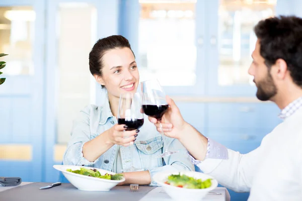 年轻的多情夫妇在餐厅庆祝家庭节日时与红酒闪烁 — 图库照片