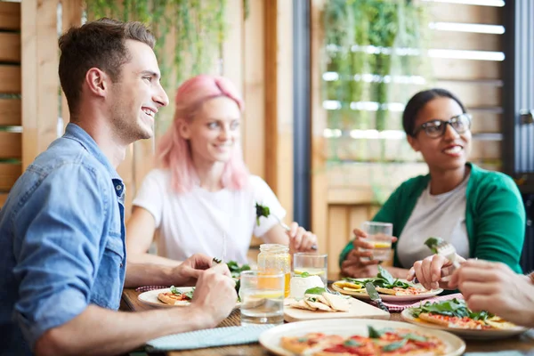 Tres Jóvenes Amigos Felices Sentados Junto Mesa Servida Mirando Amigo — Foto de Stock