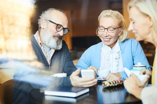 Moderna Senior Mannen Visar Två Kvinnor Något Nyfiken Sin Smartphone — Stockfoto