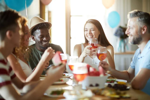 誕生日パーティーを楽しむためにお祝いのテーブルに集まった喜びの異文化の友人のグループ — ストック写真