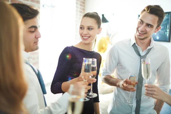 ホームパーティーでシャンパンのフルートで鳴く若いフレンドリーな人々のグループ — ストック写真