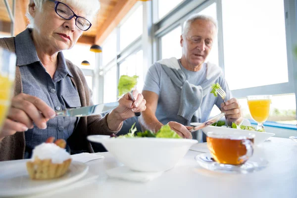 Retrato Baixo Ângulo Casal Sênior Moderno Comendo Salada Sentada Mesa — Fotografia de Stock