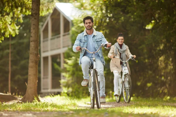 陽気な気楽な大人のカップルは 国で自転車に乗って 一緒に暖かい秋の日を楽しんで 彼らはお互いにレース — ストック写真