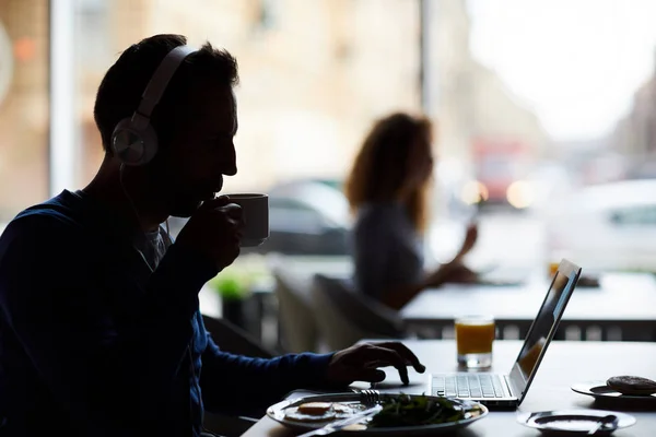 Silhouet Van Mannelijke Hipster Ondernemer Koptelefoon Zittend Aan Tafel Met — Stockfoto