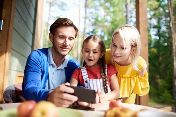 Schattige Kleine Dochter Jonge Ouders Kijken Naar Video Smartphone Terwijl — Stockfoto