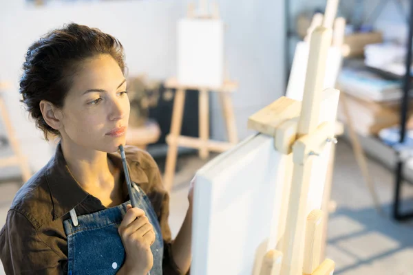 Young Pensive Woman Workwear Looking Picture While Standing Front Easel — Stock Photo, Image