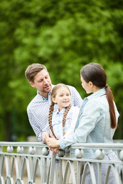 Szczęśliwy Dziewczynka Stoi Między Rodzicami Moście Parku Rozmawia Nimi — Zdjęcie stockowe