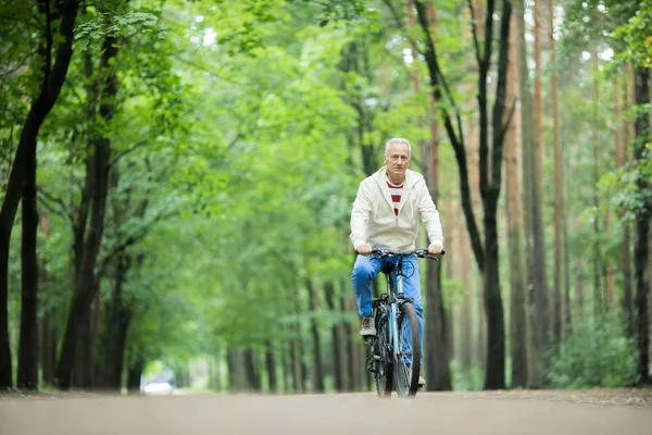 Отставной Активный Человек Катается Велосипеде Лесной Дороге Между Зелеными Деревьями — стоковое фото