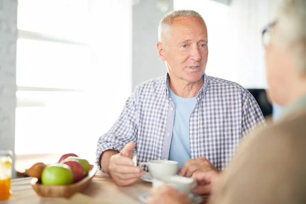 穿着休闲装的老人坐在桌旁 早餐时和妻子聊天 — 图库照片