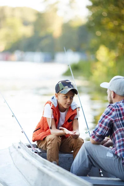 小男孩问或解释的东西 他的父亲 而都坐在船上钓鱼 — 图库照片