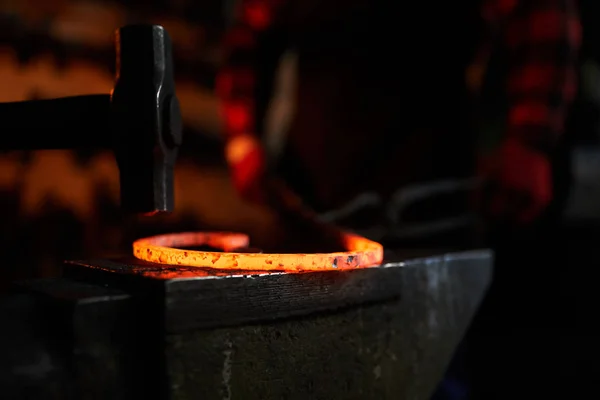 背景に鍛冶屋とアンビル上の熱い溶融金属のワークの上にハンマー — ストック写真