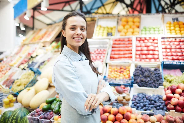 農家市場で働き 新鮮な健康的な果物や野菜を販売している自信のあるブルネットの女性食料品店に笑顔 彼女はカメラを見て — ストック写真