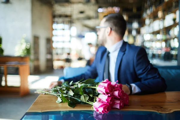 Färska Rosa Rosor Bordet Och Elegant Man Sitter Nära Och — Stockfoto