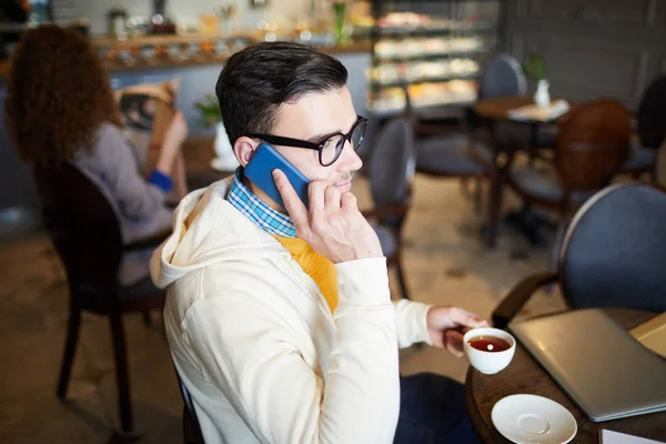 Upptagen Ung Man Casualwear Pratar Med Smartphone Samtidigt Som Kaféet — Stockfoto